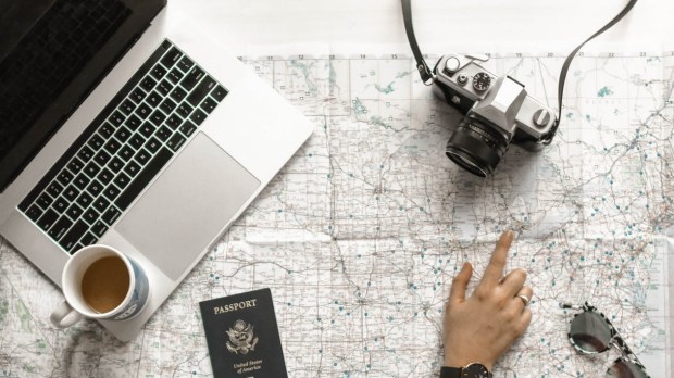 person pointing at black and gray film camera near macbook pro
